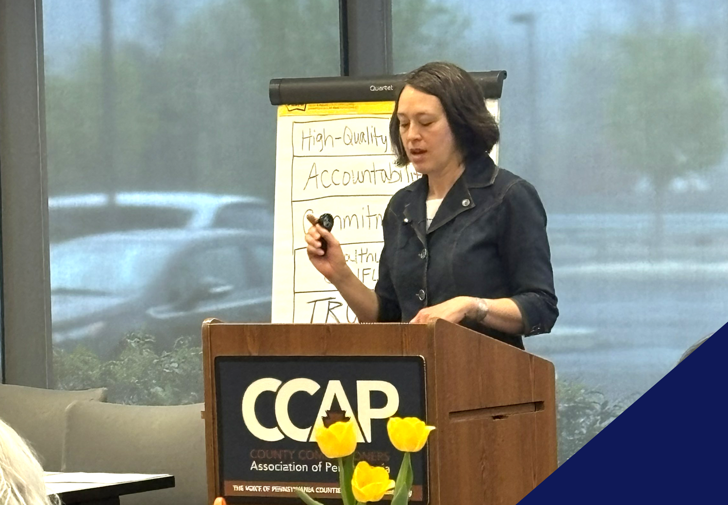 Jean standing at a podium giving a speech